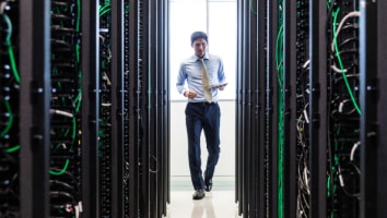 man staning in between rows of server racks